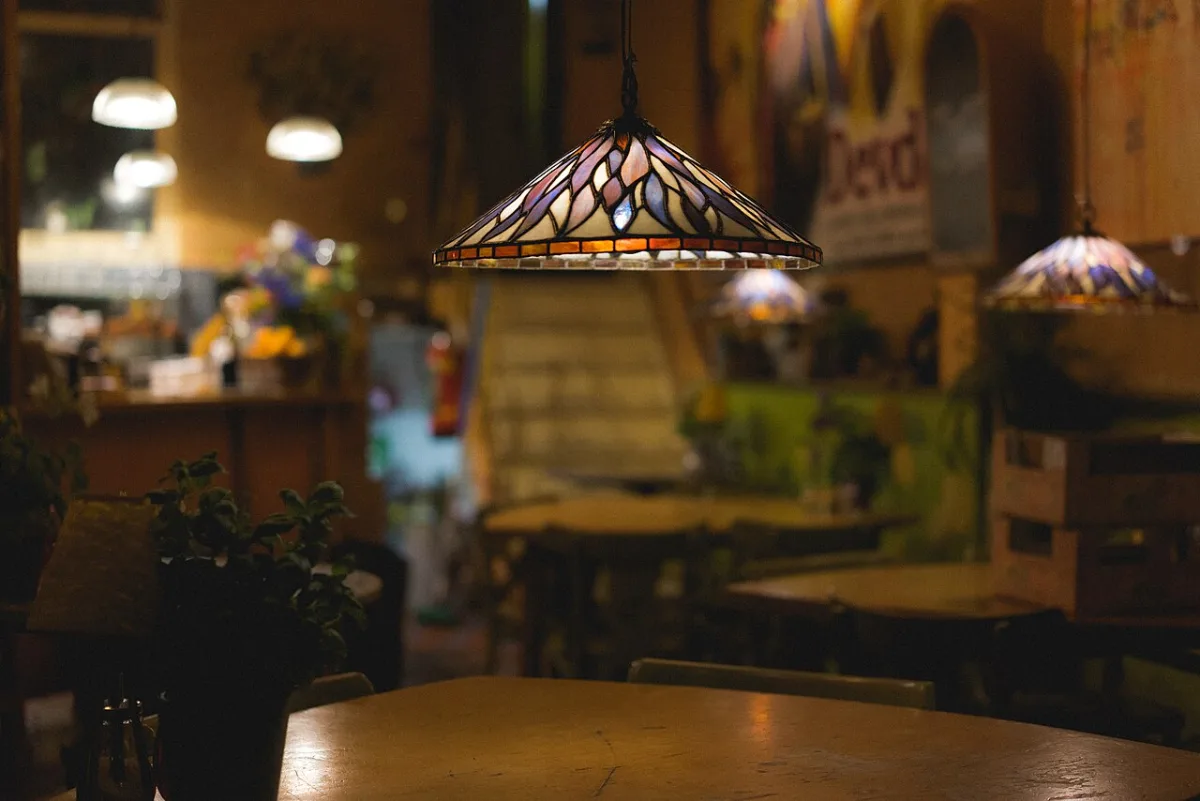 Glas-in-lood hanglamp boven een houten tafel in een gezellig café-interieur